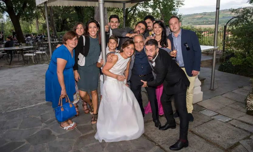 Scatto di un fotoreporter matrimonio che ritrae un gruppo di inviati scherzoso con al centro gli sposi che li circondano