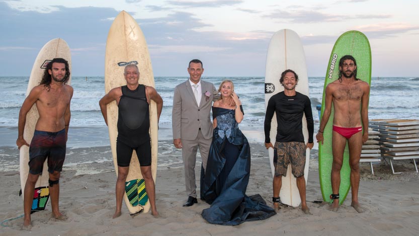 Sposi con gruppo serfisti in riva al mare