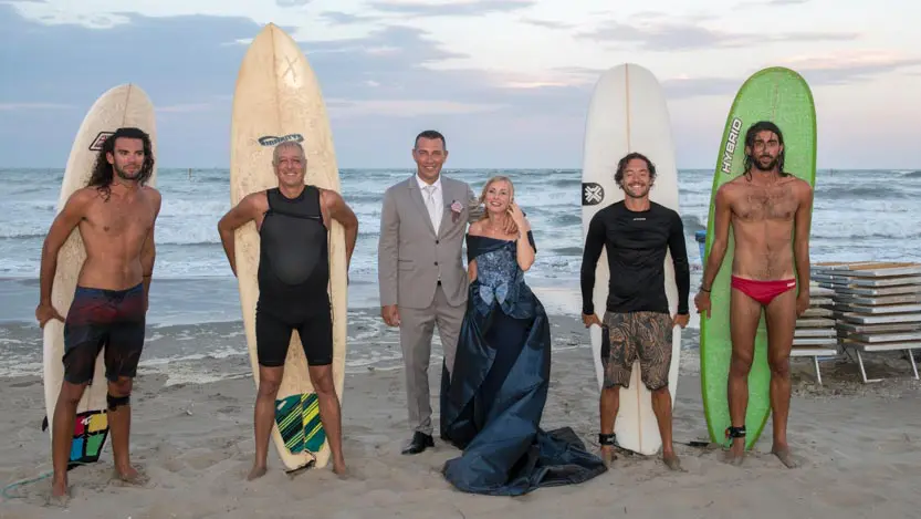 Sposi con gruppo serfisti in riva al mare