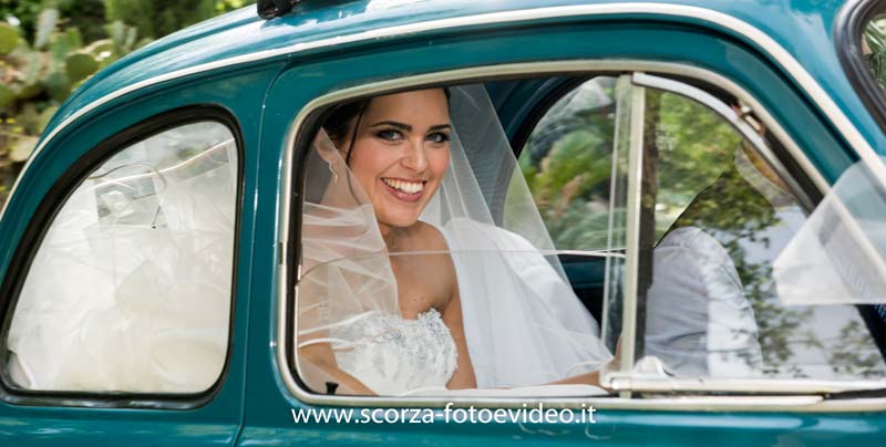 Fotografo di matrimoni sposa sorridente dietro un finestrino di una vecchia Fiat 500 di colore verde