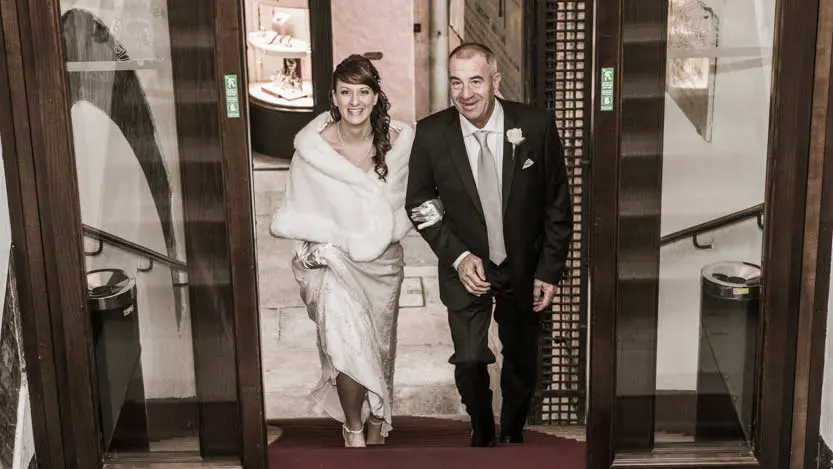Servizio fotografico matrimonio: la sposa sale le scale del municipio di Ravenna a braccetto del suo babbo molto emozionato.