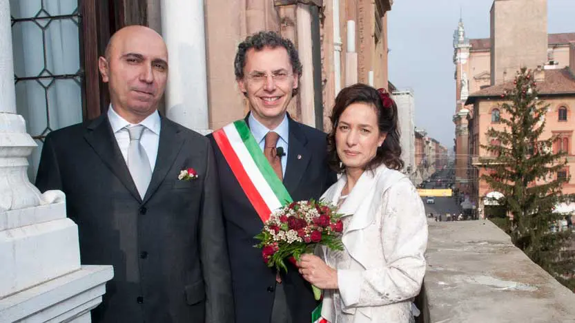 Fotografo matrimonio Bologna con gli sposi e l'assessore affacciati al balcone del municipio 