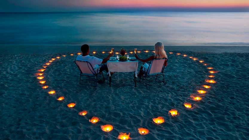 Futuri sposi al mare al tramonto in mezzo ad un cuore di lucine accese