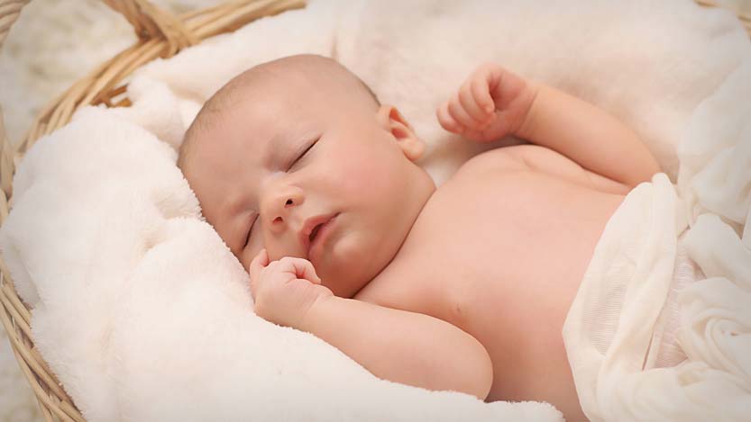 Foto neonato mentre dorme dentro un cesto