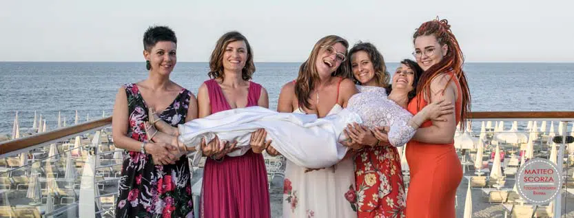 Matrimonio-sulla-spiaggia-amiche-tengono-in-braccio-la-sposa