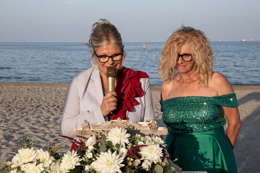 Testimone legge una frase di auguri al microfono durante un matrimonio in spiaggia a Ravenna