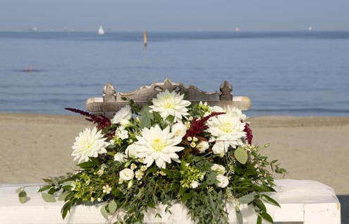 Tavolino con fiori per rito nuziale in spiaggia