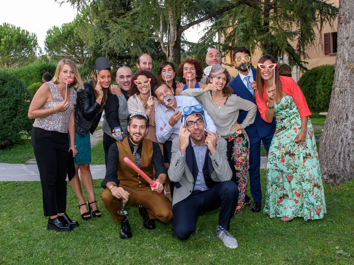 Invitati in posa con mascherine e accessori da photo booth durante la festa di matrimonio nel parco di Villa Montrona