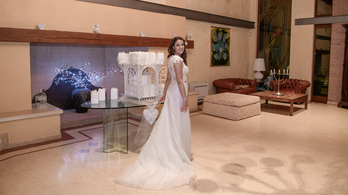 Villa Rosa Camerlona Ravenna: sposa nel salone interno con camino, divani in pelle e allestimento serale