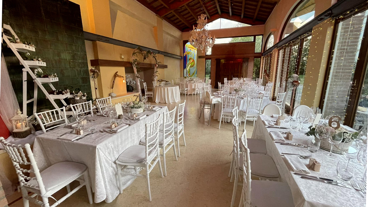 Villa Rosa Camerlona Ravenna: sala interna allestita per il ricevimento con tavoli, sedie bianche e vetrate